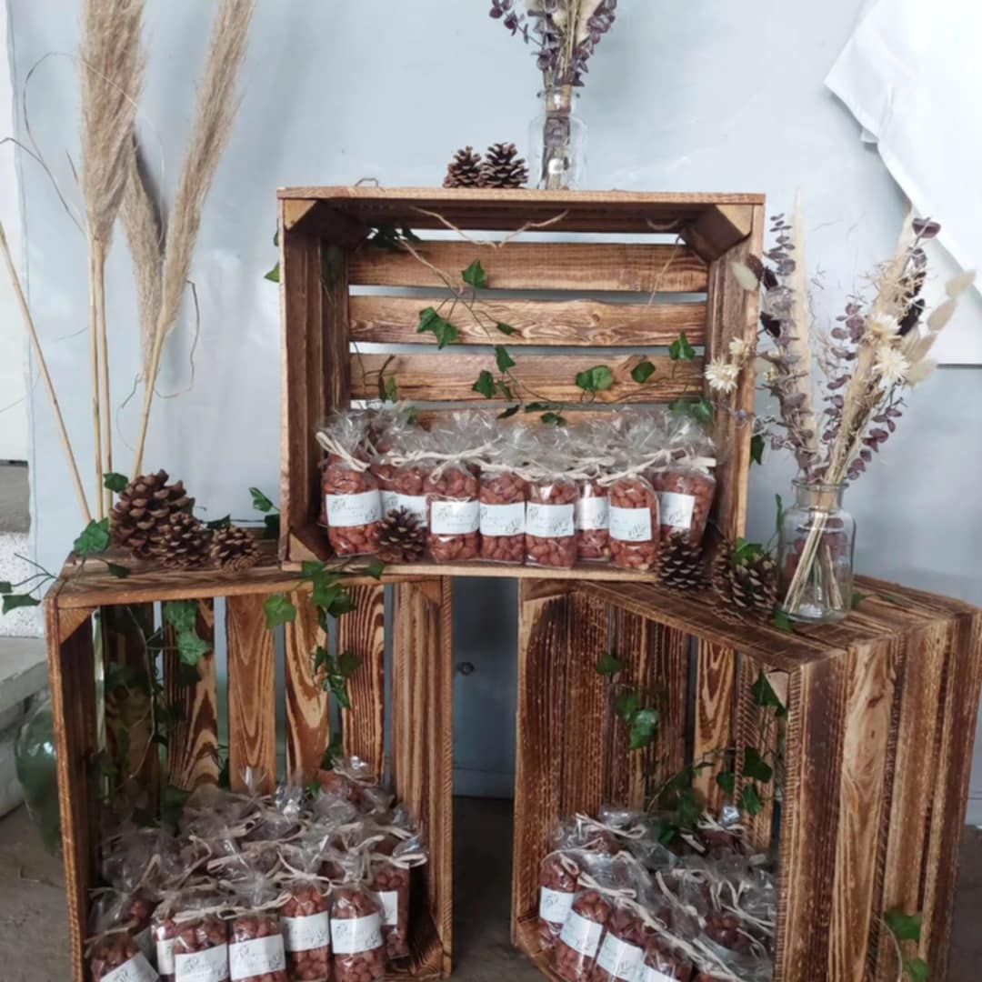 Décoration de mariage avec caisses en bois garnies de sachets de pralines artisanales personnalisées.